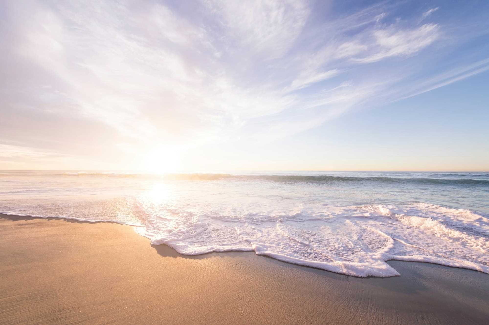 Praia ao pôr-do-sol com o mar a espraiar-se na areia